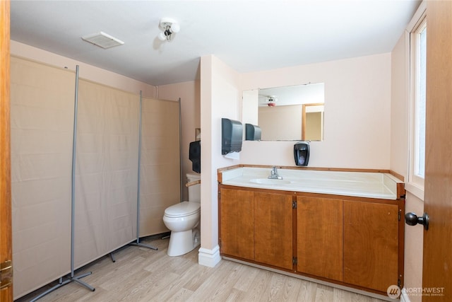 bathroom featuring toilet, wood finished floors, and vanity