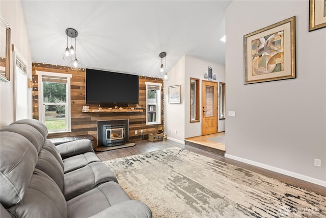 living area featuring baseboards, an accent wall, wood finished floors, and a wood stove