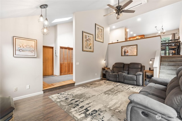 living area with high vaulted ceiling, a wall mounted AC, baseboards, and wood finished floors