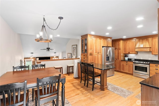 kitchen featuring premium range hood, recessed lighting, stainless steel appliances, light wood-style floors, and a breakfast bar area