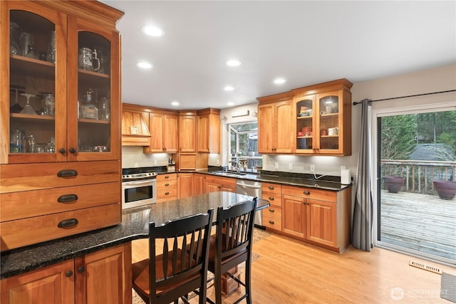 kitchen featuring visible vents, glass insert cabinets, recessed lighting, light wood-style flooring, and stainless steel appliances