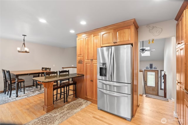 kitchen featuring light wood-style flooring, recessed lighting, a breakfast bar area, and stainless steel fridge