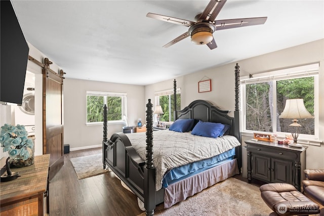 bedroom with a barn door, wood finished floors, baseboards, and ceiling fan