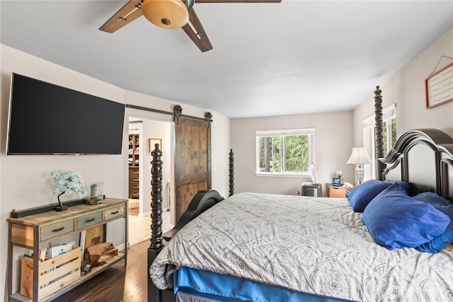 bedroom featuring a ceiling fan, a barn door, and wood finished floors