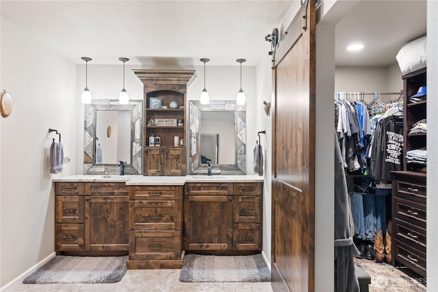 bathroom with double vanity, a spacious closet, baseboards, and a sink