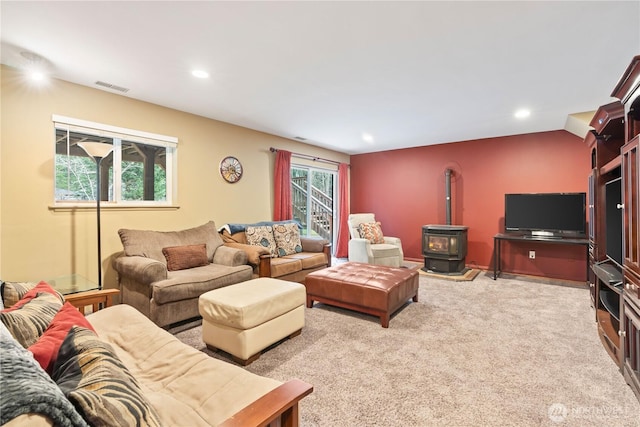 carpeted living area with visible vents, recessed lighting, and a wood stove