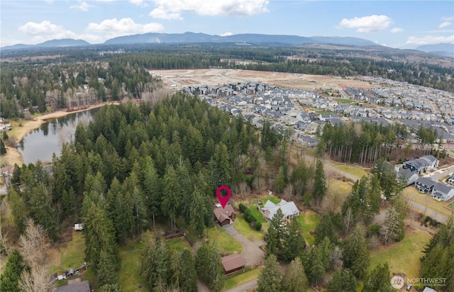 drone / aerial view featuring a forest view and a water and mountain view