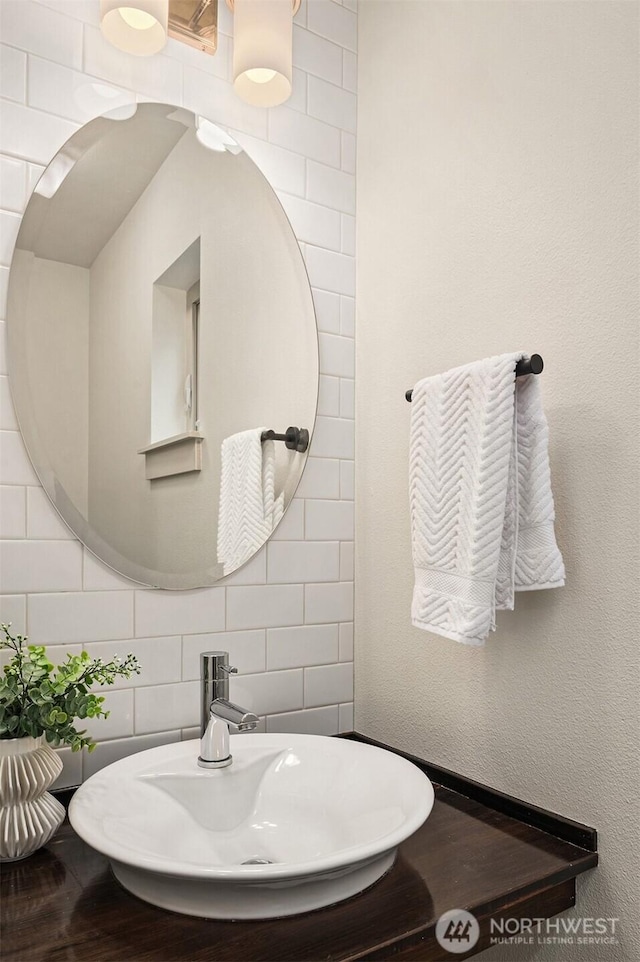 bathroom with tasteful backsplash, a sink, and tile walls