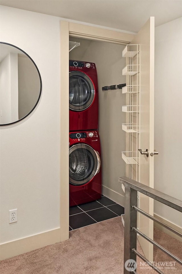 washroom with stacked washer / drying machine, dark colored carpet, dark tile patterned flooring, laundry area, and baseboards