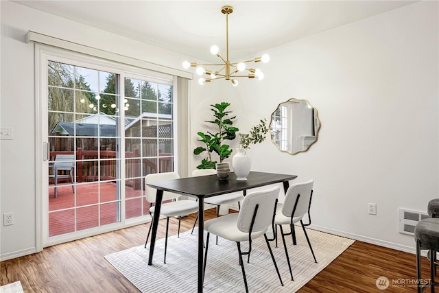 dining space with a notable chandelier, wood finished floors, visible vents, and baseboards