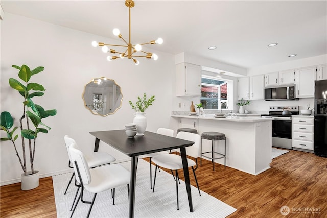 dining room with light wood-style flooring, a chandelier, baseboards, and recessed lighting