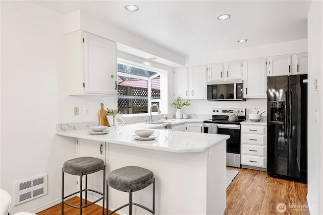 kitchen featuring white cabinetry, appliances with stainless steel finishes, light countertops, and a kitchen breakfast bar