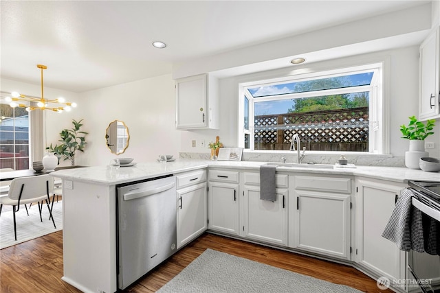 kitchen featuring stainless steel appliances, dark wood-type flooring, a peninsula, white cabinetry, and hanging light fixtures