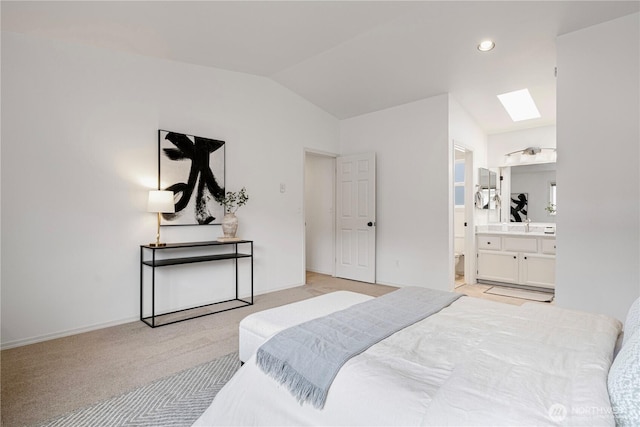 bedroom with light carpet, lofted ceiling with skylight, connected bathroom, and baseboards