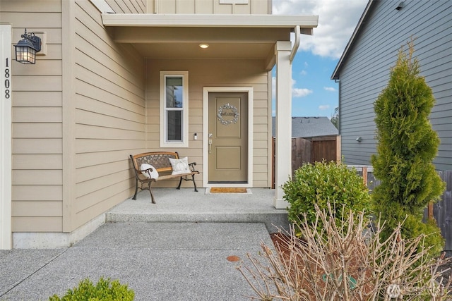 property entrance featuring covered porch, fence, and board and batten siding