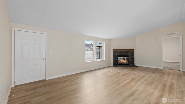 unfurnished living room with light wood-type flooring, a fireplace, visible vents, and baseboards