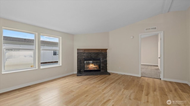 unfurnished living room featuring baseboards, visible vents, wood finished floors, and a stone fireplace