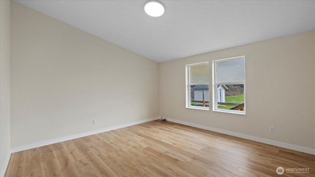 spare room with baseboards and wood finished floors