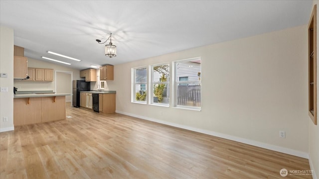 kitchen with open floor plan, a kitchen bar, freestanding refrigerator, and light wood-style floors