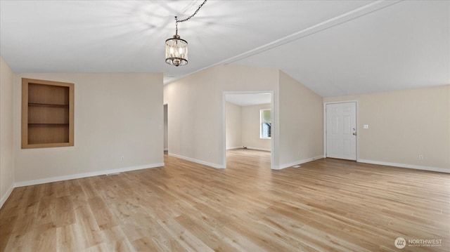 spare room with built in features, lofted ceiling, light wood-type flooring, and baseboards