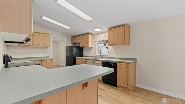 kitchen with light wood finished floors, light countertops, vaulted ceiling, light brown cabinetry, and black appliances