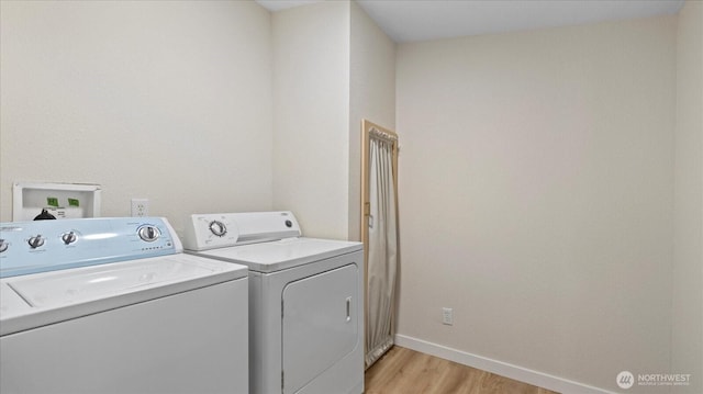 laundry area with light wood-type flooring, laundry area, washer and clothes dryer, and baseboards