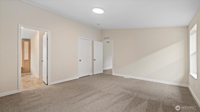 unfurnished bedroom with carpet floors, lofted ceiling, visible vents, and baseboards