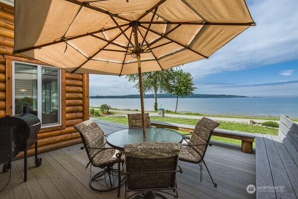 wooden terrace featuring a water view, outdoor dining area, and area for grilling