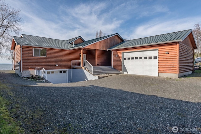 view of front facade with faux log siding, metal roof, and driveway