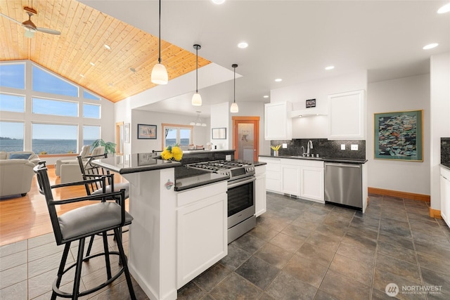 kitchen featuring dark countertops, wood ceiling, appliances with stainless steel finishes, and backsplash