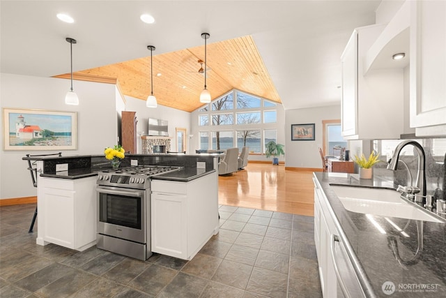 kitchen featuring open floor plan, white cabinetry, a sink, and gas range