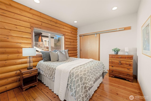 bedroom featuring light wood-style floors, recessed lighting, rustic walls, and baseboards