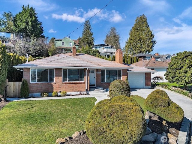 view of front of home with concrete driveway, an attached garage, fence, a front yard, and brick siding