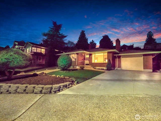 single story home featuring a garage, driveway, and brick siding