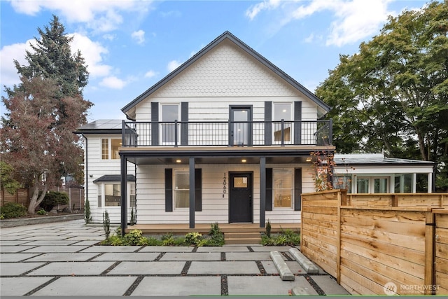 view of front of house with a balcony, covered porch, and fence