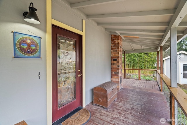 view of exterior entry with brick siding and covered porch