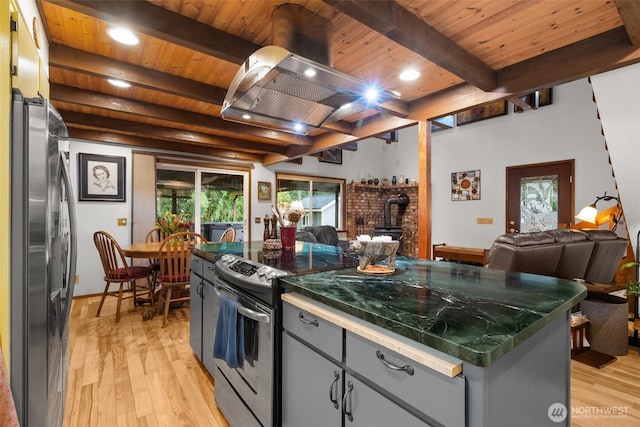 kitchen with a wood stove, wood ceiling, open floor plan, and appliances with stainless steel finishes