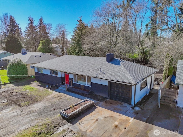 ranch-style home featuring concrete driveway, fence, a chimney, and an attached garage