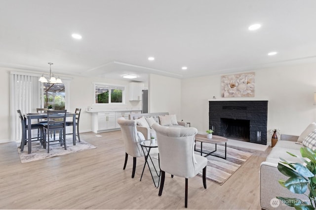 living area featuring recessed lighting, light wood-type flooring, and a brick fireplace