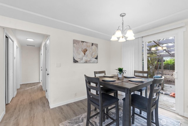 dining room featuring light wood-style floors, a chandelier, visible vents, and baseboards