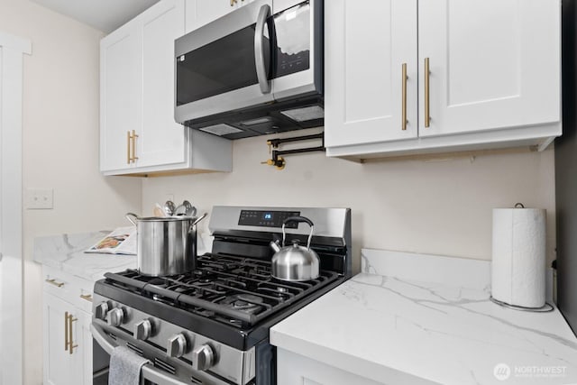 kitchen with white cabinetry, stainless steel appliances, and light stone counters