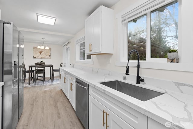 kitchen featuring a chandelier, stainless steel appliances, a sink, light wood-style floors, and white cabinets