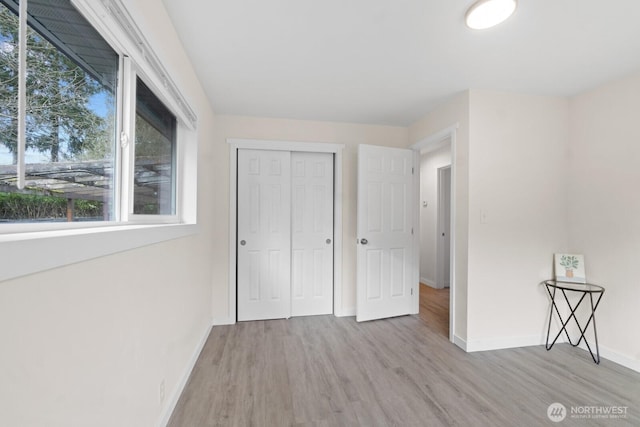 unfurnished bedroom with a closet, baseboards, and wood finished floors