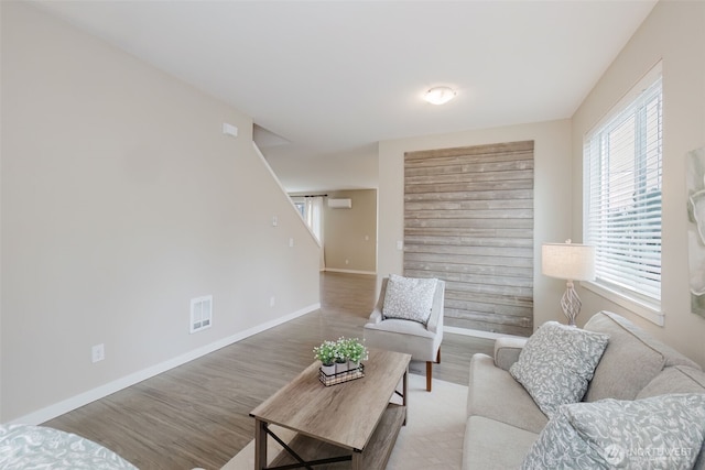 living area featuring baseboards, visible vents, and light wood finished floors