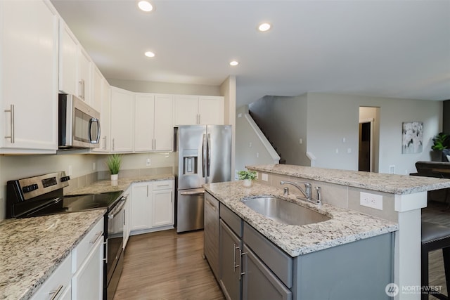kitchen featuring a center island with sink, recessed lighting, dark wood-style flooring, a sink, and appliances with stainless steel finishes