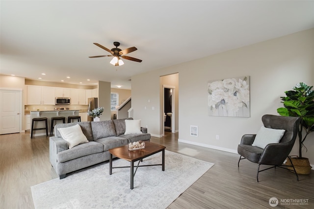 living room with light wood finished floors, visible vents, baseboards, ceiling fan, and recessed lighting