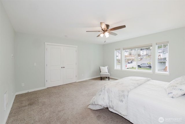 carpeted bedroom featuring a closet, a ceiling fan, and baseboards