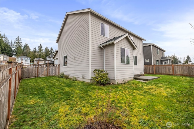 rear view of property with a yard and a fenced backyard