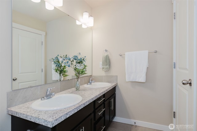 full bathroom with double vanity, tile patterned floors, baseboards, and a sink
