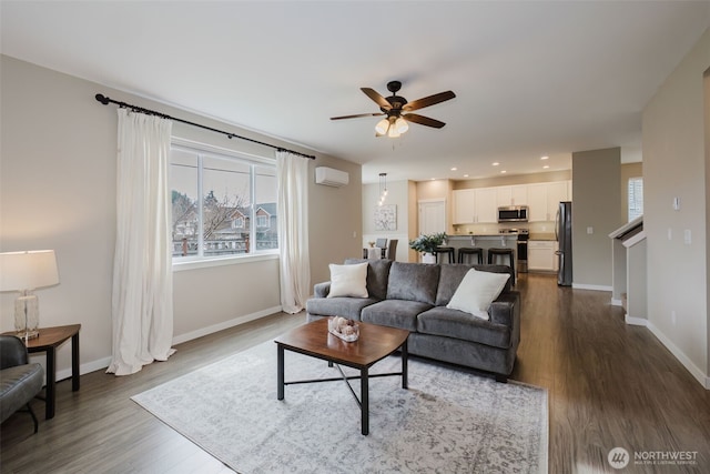 living room with a wall unit AC, dark wood-style floors, baseboards, and ceiling fan
